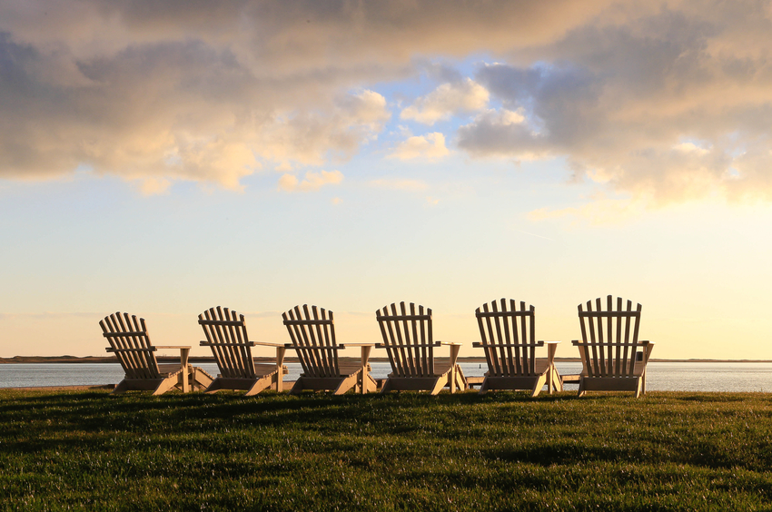 Six Adirondack chairs sitting by the Sea